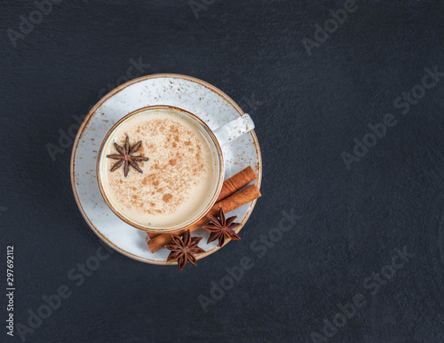 Indian Masala chai tea. Traditional Indian hot drink with milk and spices on dark stone table background. Top view, flat lay. Copy space