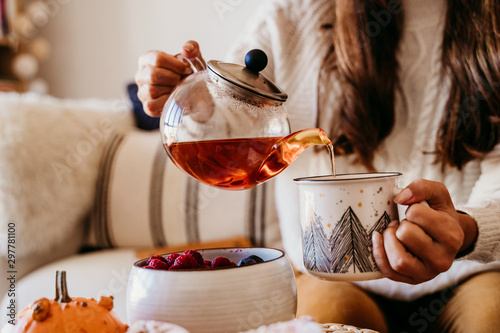 woman having a cup of tea at home during breakfast. Cute golden retriever dog besides. Healthy breakfast with fruits and sweets. lifestyle indoors