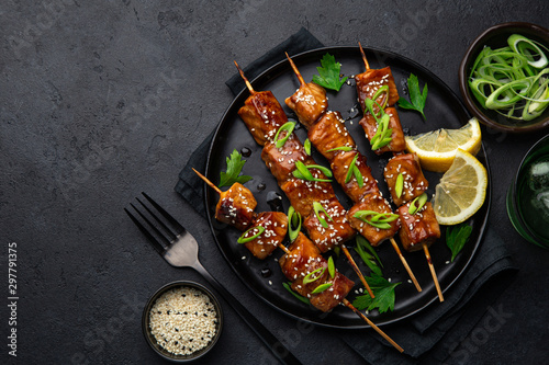 Teriyaki salmon skewers on black plate