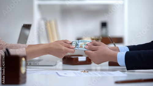 Male and female hands pulling money, dividing marital property during divorce
