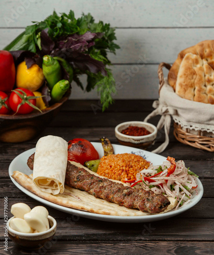 adana kebab on pita bread served with bulgur and onion slices