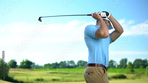 Male golfer hitting ball performing draw position, professional sport, hobby