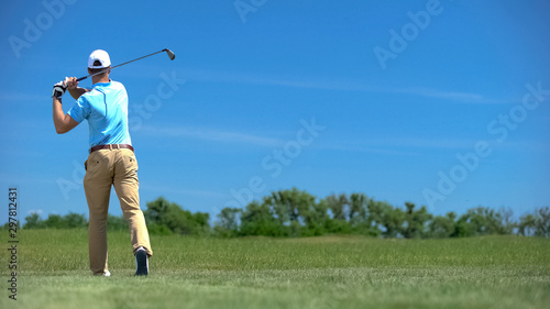 Skilled golf player performing swing position, hitting ball on course, training