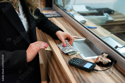 Money exchange concept / Female hand with money at cash desk. Currency exchange concept.