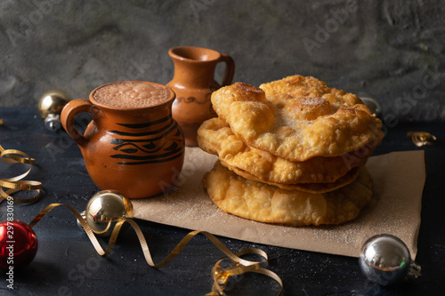 mexican fritter dusted with sugar also called "buñuelos" and hot chocolate on dark background