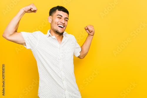 Young hispanic man raising fist after a victory, winner concept.