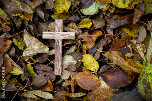 wooden cross on leaves in autumn