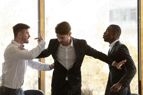 Male colleague set apart angry diverse businessmen fighting in office