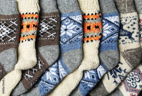 Different knitted woolen socks as background, top view