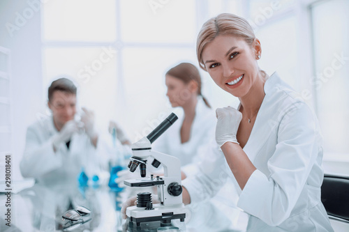 successful female scientist sitting in front of a microscope