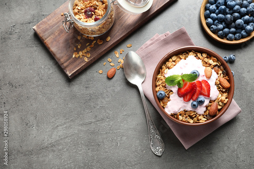 Delicious yogurt with granola and berries served on grey table, flat lay. Space for text
