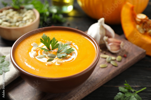 Delicious pumpkin soup in bowl on wooden table
