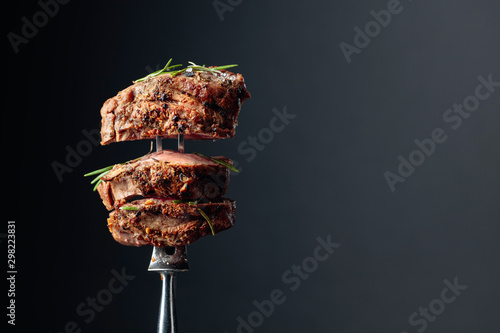 Grilled ribeye beef steak with rosemary on a black background.