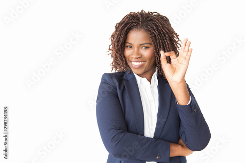 Satisfied happy customer making ok gesture. Young black business woman standing isolated over studio background, showing Okay sign. Approval concept