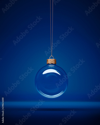 Glass christmas bauble hanging in front of luxury dark blue background.