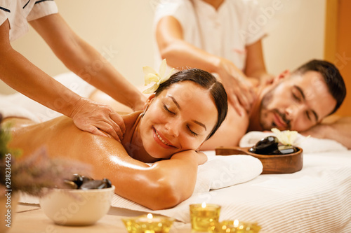 Happy couple enjoying a day at spa while having back massage.