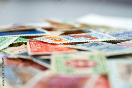 Closeup view on a variety of multi-colored postage stamps from different countries and years. Selective focus