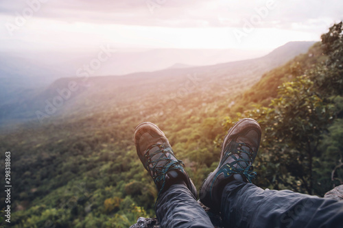 Traveler resting man hiking boots having fun and enjoying wonderful breathtaking the forest mountain rocks view. Freedom travel concept. hiking shoes and man legs.