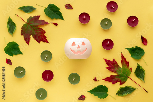Leaves, candles, pumpkin on yellow background. Autumn, fall, halloween concept. Top view, flat lay.