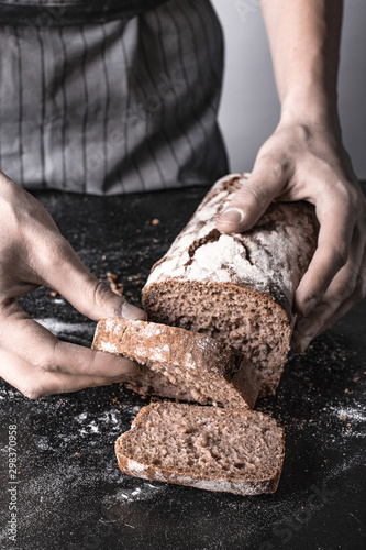 Trzymanie bochenka chleba w dłoniach na szarym tle w stylu rustykalnym