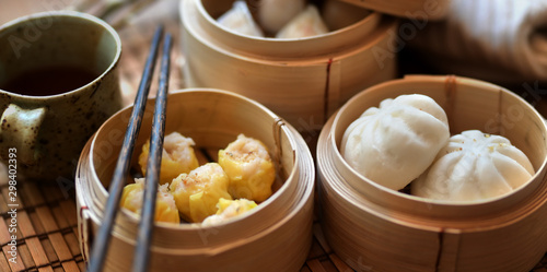 Chinese steamed dumpling and steamed pork bun in a bamboo steamer with chopstick