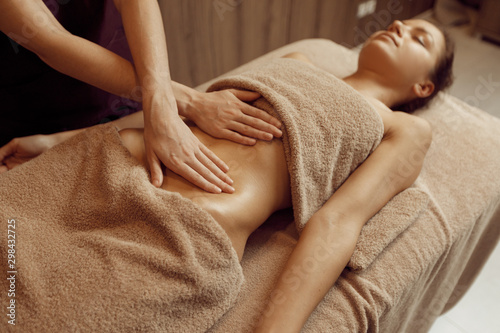 Female masseur pampering stomach to young woman