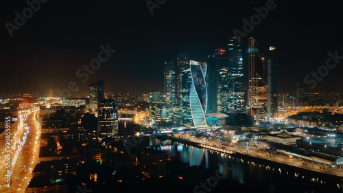 Beautiful view from above to Moscow City Center on the night with bright glittering lights of buildings, streets and traffic. Camera slowly moves towards skyscrapers showing amazing cityscape.