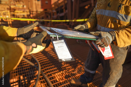 Senior miner supervisor holding and hand over isolation safety control lock box permit to work board to workmate during shift changing on two weeks shut down operation construction site Perth