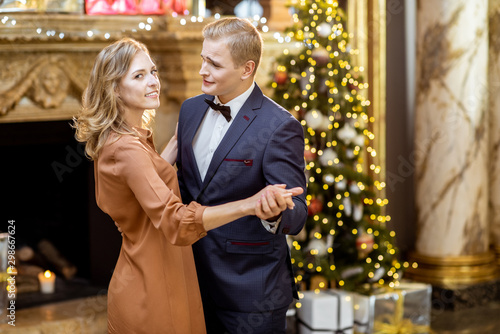 Couple dancing near the christmas tree indoors