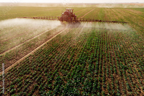 Tractor spraying fertilizer or pesticides on field with sprayer