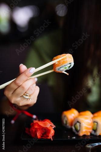 Hands eat sushi with chopsticks in cafe