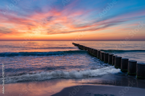 Baltic sea seascape at sunset, Poland, wooden breakwater and waves