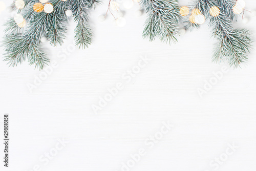 White wooden background decorated wit h frosty fir branches and lights, Christmas of New Year holiday frame