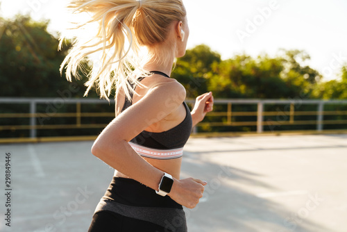 Image of attractive fitness woman wearing tracksuit running outdoors