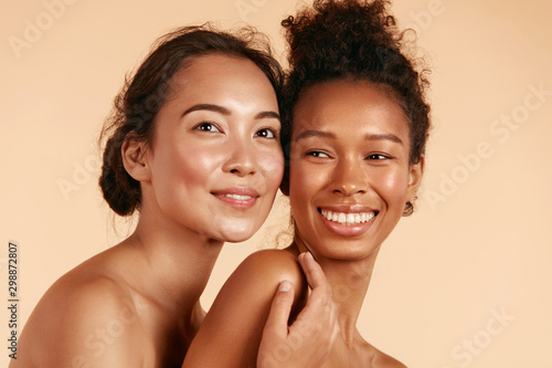 Beauty. Smiling women with perfect face skin and natural makeup portrait. Beautiful happy asian and african girl models with different types of skin on beige background. Spa skin care concept