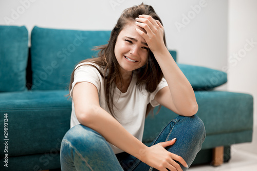 beautiful young woman crying feeling very depressed sitting on floor shouting loud with her hand touching her head tough life