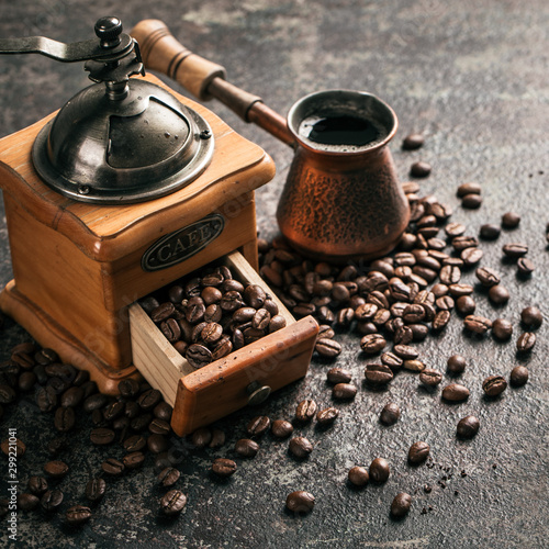 Coffee with coffee grinder and coffee beans on dark textured background.