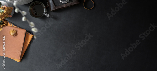 Top view of dark trendy workplace with copy space and office supplies on black leather desk