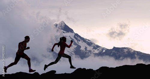 Running people athletes silhouette trail running in mountain summit background. Man and woman on run training outdoors active fit lifestyle.