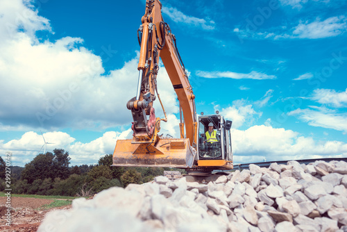 Woman operating an excavator on road works construction site