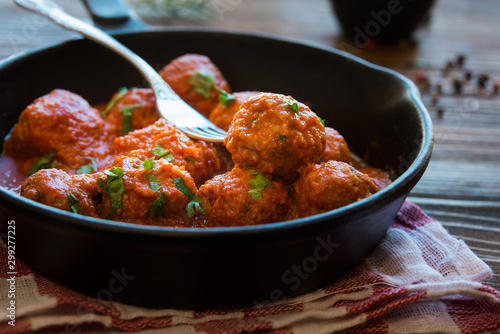 Homemade meatballs with tomato sauce and parsley in a frying pan