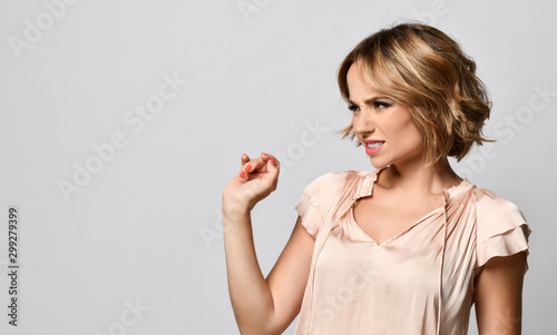 Young woman disgusted squeamishness over gray wall background.