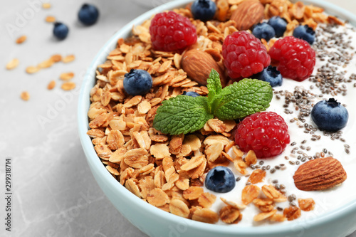 Tasty homemade granola with yogurt and berries on light grey table, closeup. Healthy breakfast