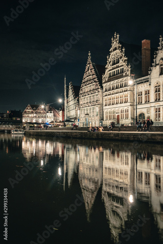 Panoramic view of Graslei in the historic city center of Ghent at night with reflections on the Leie river, Ghent, East Flanders, Belgium