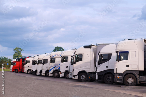 Various types of trucks in the parking lot next to the motorway.