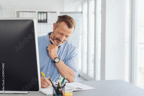 Thoughtful businessman writing notes in the office