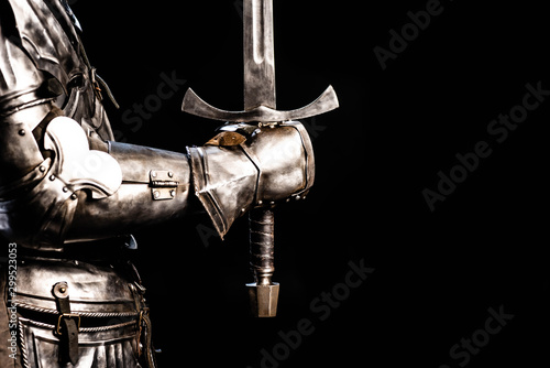 cropped view of knight in armor holding sword isolated on black