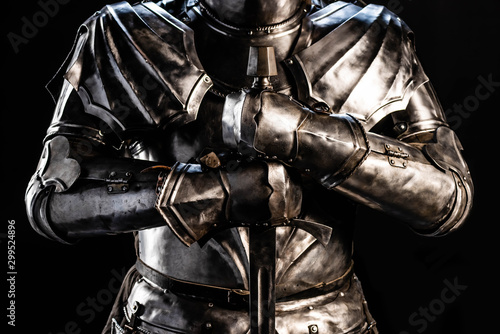 cropped view of knight in armor holding sword isolated on black