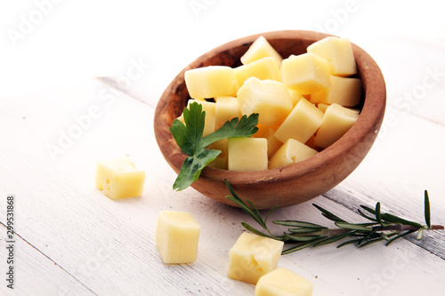 cheese cubes in wooden bowl with parsley. cheese pieces on table