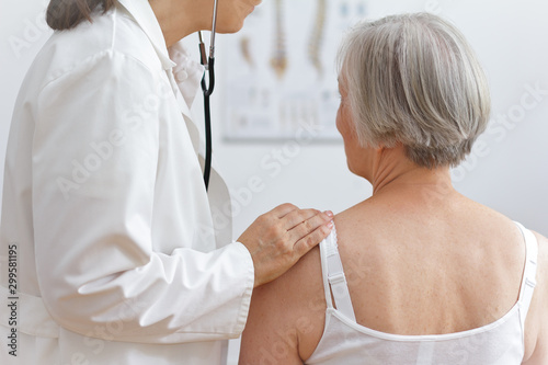 Health care concept: female doctor auscultating the heart of a senior patient with a stethoscope.